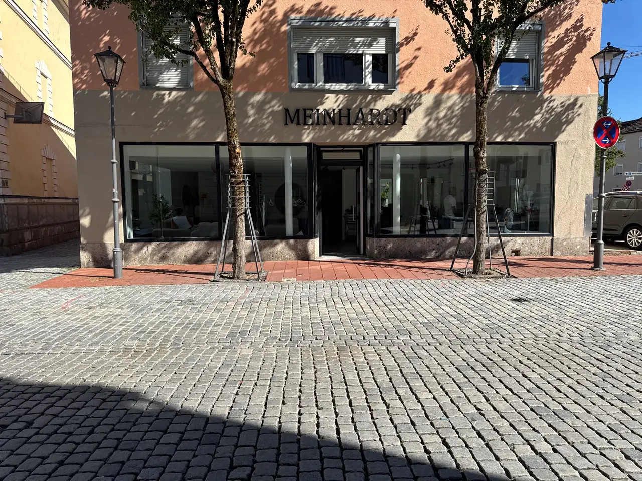 Fassade von Maison Meinhardt mit Schriftzug, Bäumen und Kopfsteinpflaster